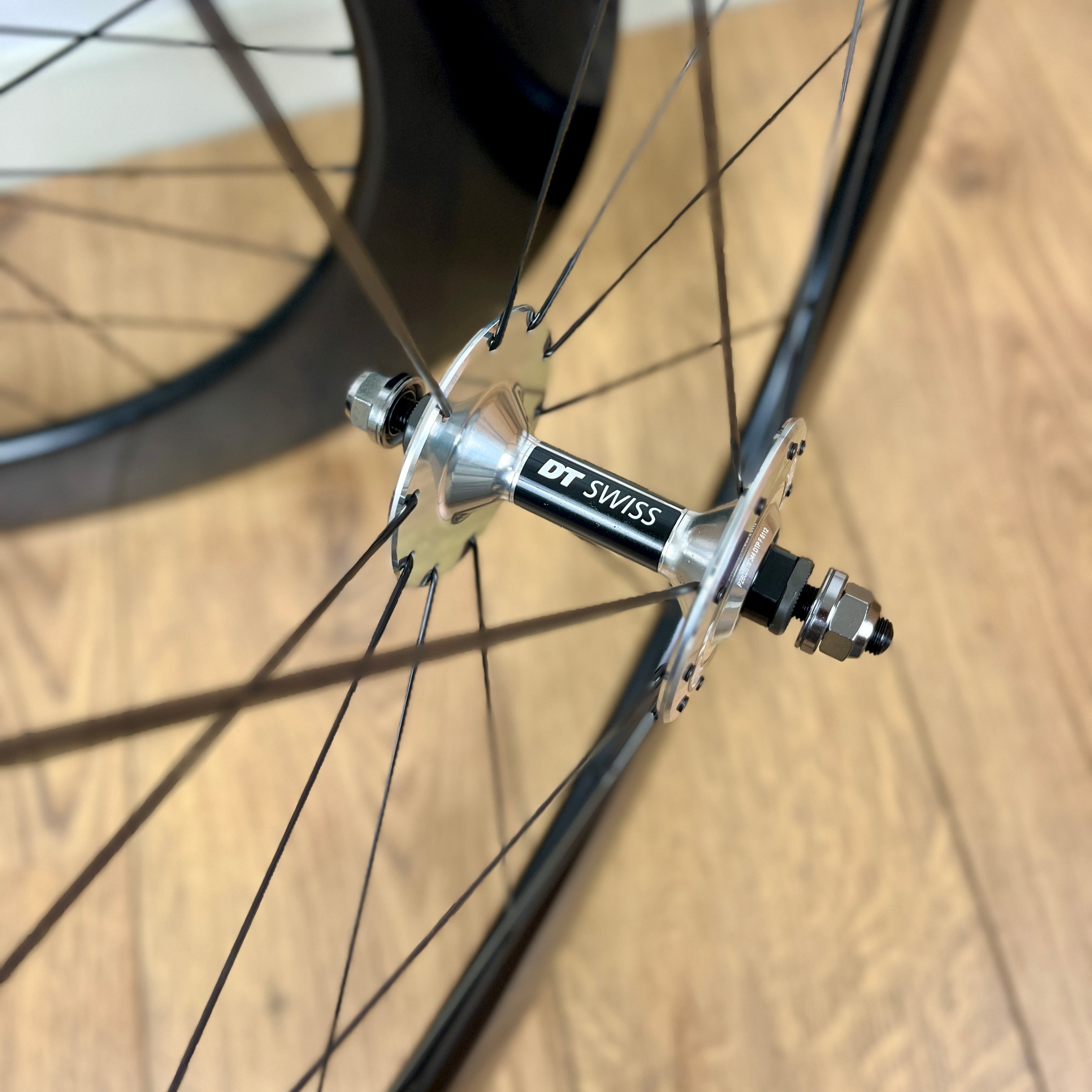Close-up of a bicycle wheel hub with DT Swiss branding on a wooden surface